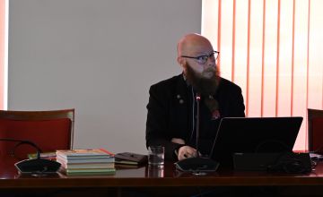Siedząca przy stole osoba prowadząca konferencję